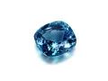 A cushion-cut blue gemstone, likely sapphire, what is September's birthstone, sparkles against a white background.