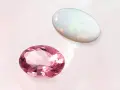 Pink tourmaline and opal, the two birthstones for October, shimmer on a pale background.