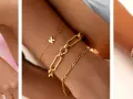 Showcasing the stacking bracelets trend with gold and silver bangles, chains, and a personalized initial charm.