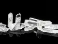Raw danburite crystals on a black reflective surface, hinting at their powerful danburite metaphysical properties for spiritual growth and angelic connection.