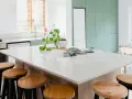 A modern kitchen island with a speckled synthetic quartz countertop, surrounded by wooden stools.
