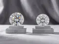 Two brilliant-cut diamonds, one labeled IGI and the other GIA, are displayed on pedestals. This highlights the difference between natural and simulated diamond grading.