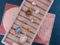 A collection of antique jewelry with opal stones, featuring rings with iridescent opals in gold settings, displayed in a velvet ring holder.