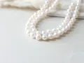 A double strand of luminous white pearls, symbolizing purity and elegance. The silver pearl meaning is often associated with wisdom and serenity.