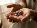 Hands hold a pendant and ring with deep purple amethyst. These beautiful stones are found in Brazil, Uruguay, and other locations worldwide.