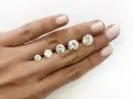 Five round brilliant cut diamonds are displayed on a hand, showing a progression in size. The largest diamond is what is considered a big diamond.