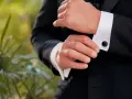 A man fastens his tuxedo cuff with elegant, black onyx cufflinks, showcasing classic types of cufflinks.
