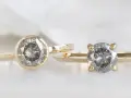 Two gold rings, one with a bezel setting and the other with a prong setting, showcase their unique diamond styles.