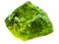 A rough, translucent green crystal, like an emerald, represents growth, renewal, and prosperity.