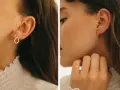 Chic ear stack ideas featuring delicate gold earrings: a teardrop charm, a curved bar, and tiny diamond studs.