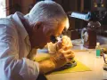 A watchmaker, wearing a loupe, meticulously works on a watch, demonstrating how to fix a watch with precision tools.