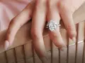 A hand displays a stunning oval diamond engagement ring, sparking the question: are brilliant earth diamonds real?