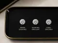 Three round brilliant cuts: a mined diamond, a diamond simulant, and cubic zirconia, displayed on a black tray.