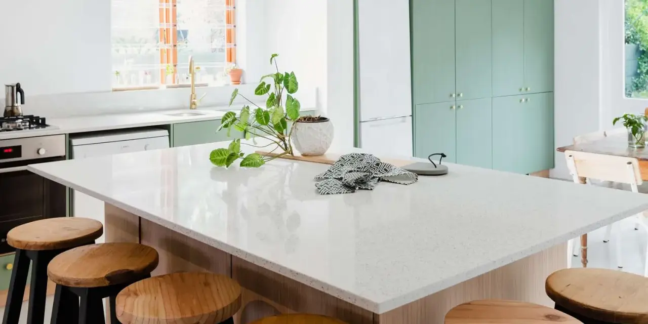 A modern kitchen island with a speckled synthetic quartz countertop, surrounded by wooden stools.