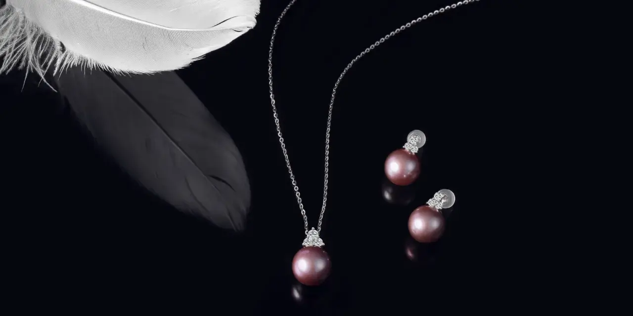A delicate necklace and earrings featuring pink pearls, symbolizing love and purity. A white feather rests nearby, adding an ethereal touch.