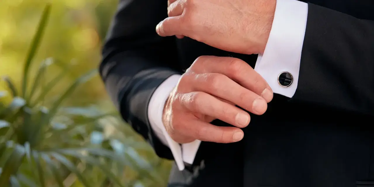 A man fastens his tuxedo cuff with elegant, black onyx cufflinks, showcasing classic types of cufflinks.
