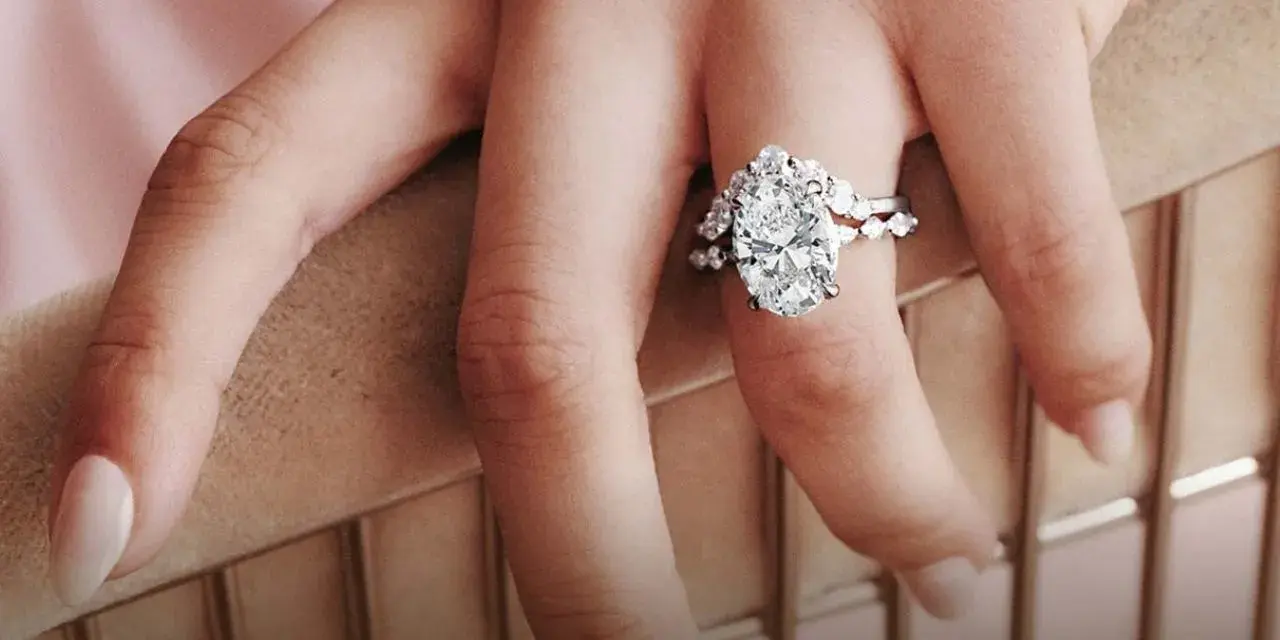 A hand displays a stunning oval diamond engagement ring, sparking the question: are brilliant earth diamonds real?