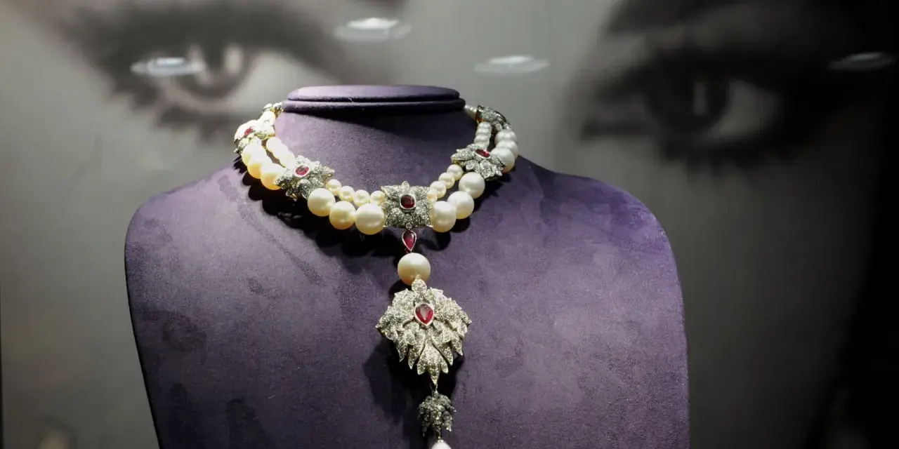A stunning pearl and ruby necklace, reminiscent of "La Peregrina," drapes elegantly over a purple bust.