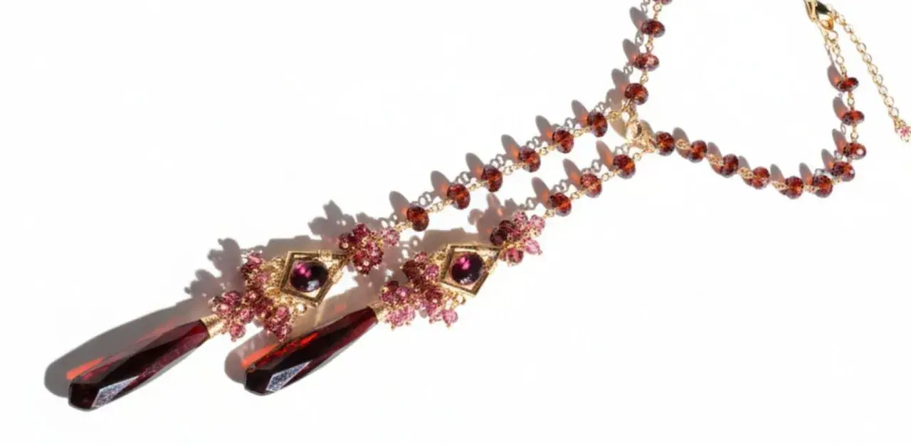 A gold necklace with various types of garnet, featuring deep red teardrop pendants and smaller faceted garnets in a rich, warm hue.