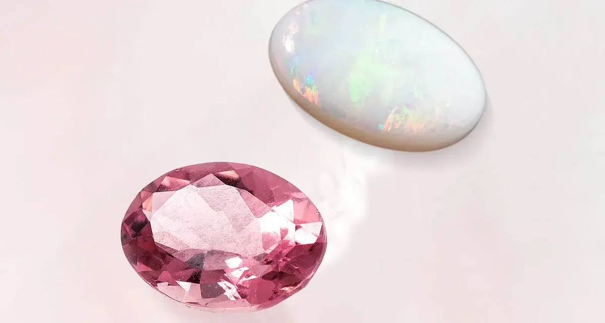 Two oval gemstones, a pink tourmaline and a white opal, are displayed. The opal's play-of-color makes it a perfect october 27 birthstone.