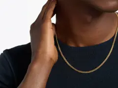 A man's hand touches his neck, showcasing a sleek gold chain length for men.