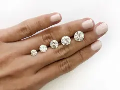 Five round brilliant cut diamonds are displayed on a hand, showing a progression in size. The largest diamond is what is considered a big diamond.