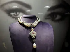 A stunning pearl and ruby necklace, reminiscent of "La Peregrina," drapes elegantly over a purple bust.