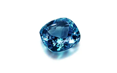 A cushion-cut blue gemstone, likely sapphire, what is September's birthstone, sparkles against a white background.