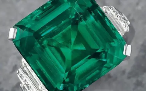 A stunning emerald ring, showcasing a large, square-cut green gemstone, possibly the most expensive gemstone, surrounded by smaller diamonds.