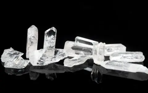 Raw danburite crystals on a black reflective surface, hinting at their powerful danburite metaphysical properties for spiritual growth and angelic connection.
