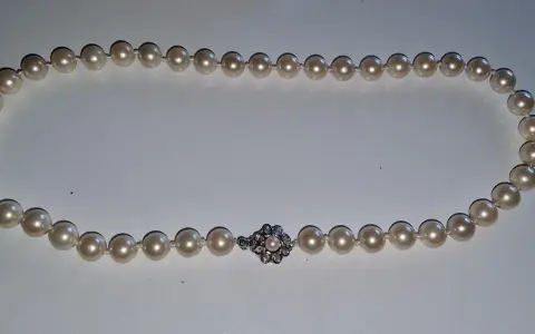 A pearl necklace with a diamond clasp. Learn how to tell if pearls are real by examining their luster and surface imperfections.