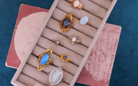 A collection of antique jewelry with opal stones, featuring rings with iridescent opals in gold settings, displayed in a velvet ring holder.