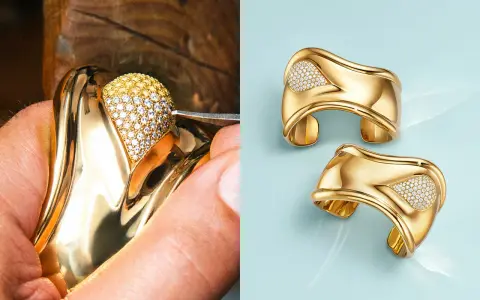 A jeweler meticulously sets diamonds on a gold ring, a testament to Elsa Peretti's exquisite designs. Two finished gold cuffs with diamond accents gleam on a light blue background.