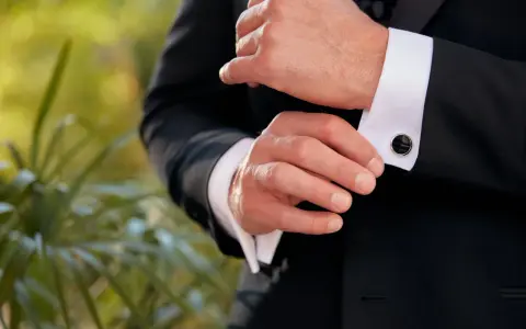 A man fastens his tuxedo cuff with elegant, black onyx cufflinks, showcasing classic types of cufflinks.