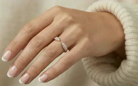 A hand with French manicured nails wears a sparkling rose gold ring. Rose gold is far from out of style!