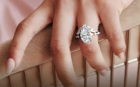 A hand displays a stunning oval diamond engagement ring, sparking the question: are brilliant earth diamonds real?