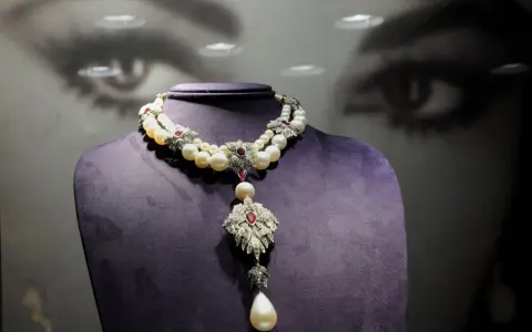 A stunning pearl and ruby necklace, reminiscent of "La Peregrina," drapes elegantly over a purple bust.