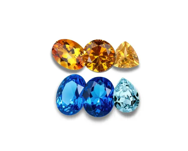 A collection of faceted gemstones, including warm orange and yellow topaz birthstones, and cool blue and aquamarine stones, arranged in two rows.