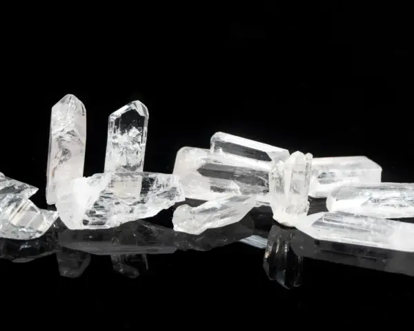 Raw danburite crystals on a black reflective surface, hinting at their powerful danburite metaphysical properties for spiritual growth and angelic connection.