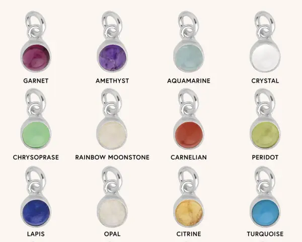 A collection of silver charms, each featuring a different colored gemstone representing birthstones for months: Garnet, Amethyst, Aquamarine, Crystal, Chrysoprase, Rainbow Moonstone, Carnelian, Peridot, Lapis, Opal, Citrine, and Turquoise.