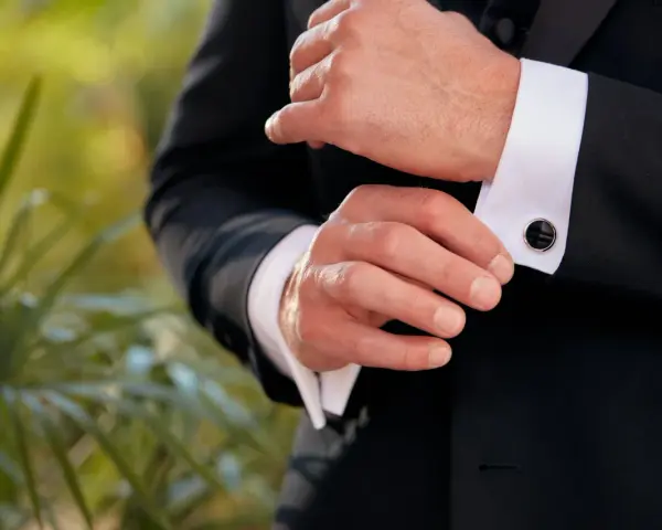 A man fastens his tuxedo cuff with elegant, black onyx cufflinks, showcasing classic types of cufflinks.