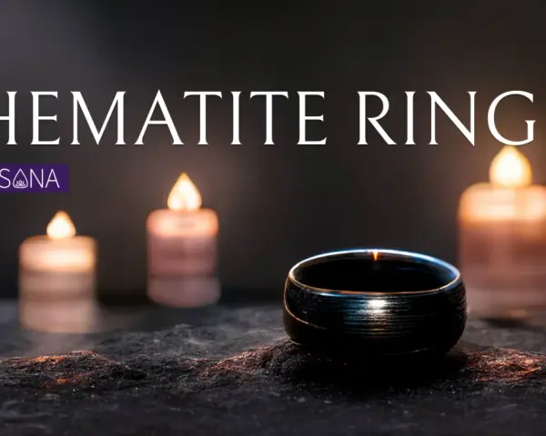 A dark hematite ring sits on a textured surface, illuminated by soft candlelight. Discover the hematite ring meaning.