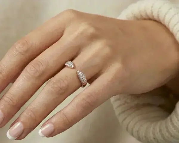 A hand with French manicured nails wears a sparkling rose gold ring. Rose gold is far from out of style!