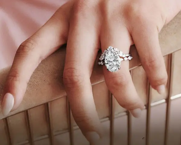A hand displays a stunning oval diamond engagement ring, sparking the question: are brilliant earth diamonds real?