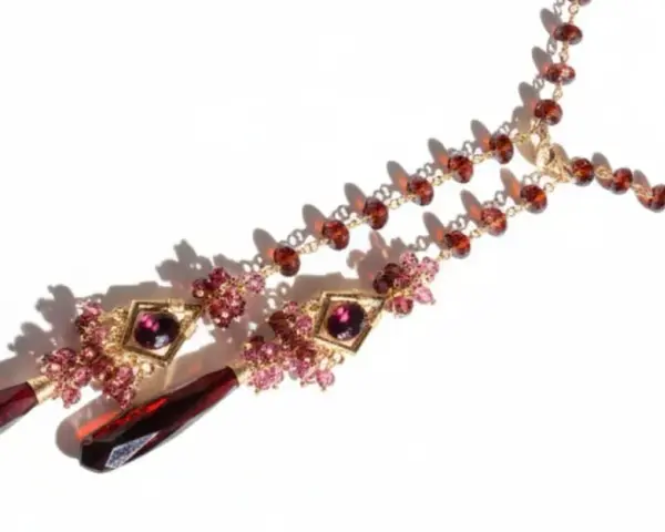 A gold necklace with various types of garnet, featuring deep red teardrop pendants and smaller faceted garnets in a rich, warm hue.