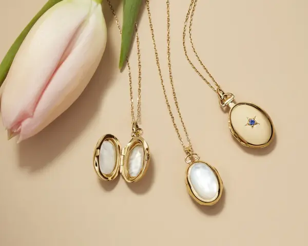 Gold lockets featuring mother of pearl, a lustrous material from shells, lie beside a delicate pink tulip.