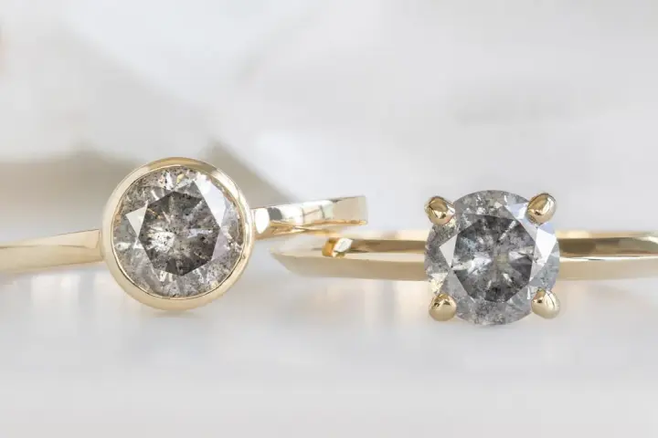 Two gold rings, one with a bezel setting and the other with a prong setting, showcase their unique diamond styles.