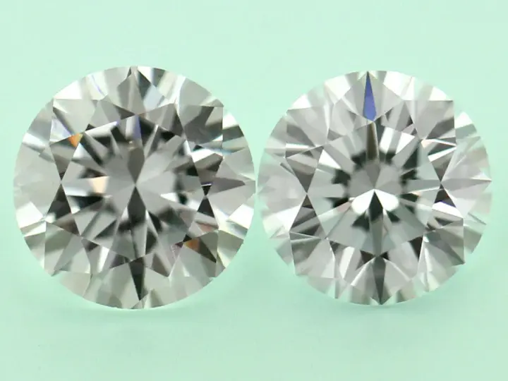 Two round brilliant cut diamonds, one a diamond simulant and the other lab grown, are shown side-by-side on a pale green background.