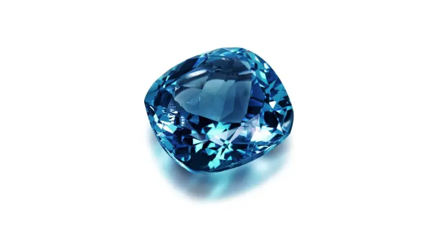 A cushion-cut blue gemstone, likely sapphire, what is September's birthstone, sparkles against a white background.