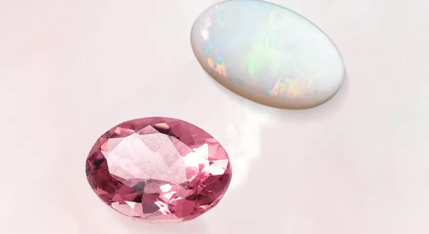 Pink tourmaline and opal, the two birthstones for October, shimmer on a pale background.